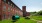 a large green barrel in front of a brick building