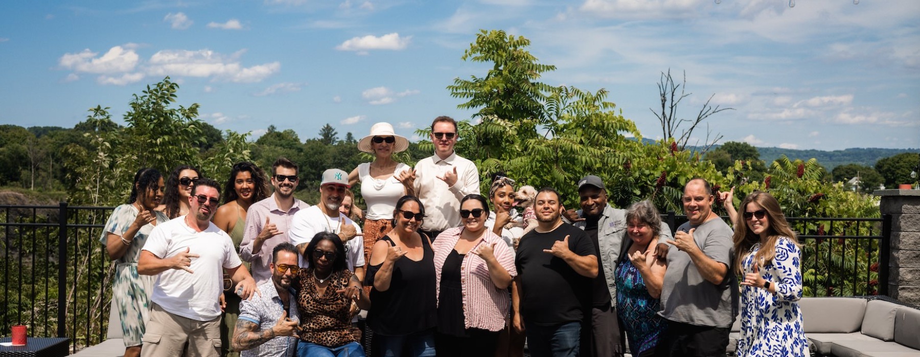 a large group of people posing for a picture with trees behind them
